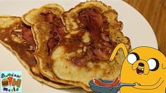 two pancakes with bacon on them are sitting on a plate next to a cartoon character