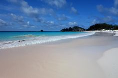 a sandy beach with blue water and white sand