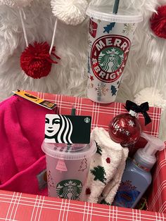 starbucks coffee cup and other items on a red plaid tablecloth with pom - poms