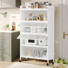 a white kitchen shelving unit with lots of items on the shelves and in front of it