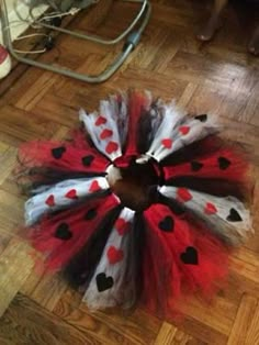 a red, white and black heart tutule is on the floor next to a cat