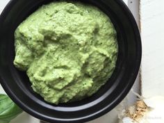 a black bowl filled with green guacamole on top of a white table