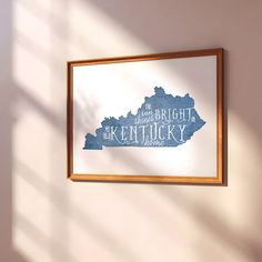 a wooden frame hanging on the wall with a blue kentucky map cut out in it