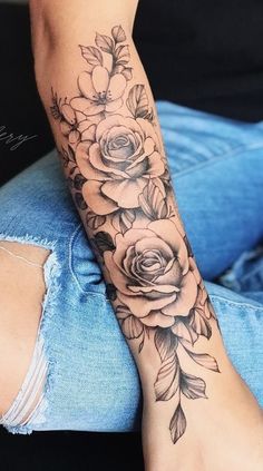 a woman's arm with flowers and leaves on it