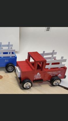 two red and blue toy trucks sitting on top of a wooden table next to each other