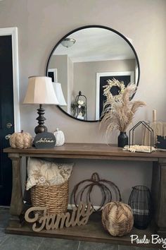 a wooden table topped with a mirror and baskets filled with pumpkins next to a lamp