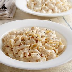 two white plates filled with pasta and chicken