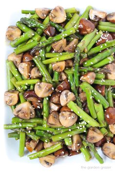 asparagus and mushrooms with sesame seeds on a white plate