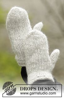 a pair of white knitted mittens sitting on top of a black object