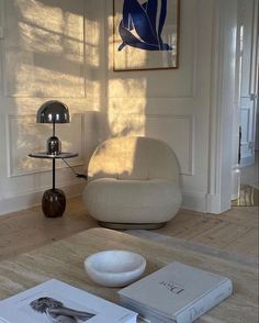 a living room filled with furniture and a book on top of a wooden table next to a lamp