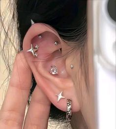 a person with some piercings on their ear and one is holding onto the other