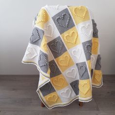 a crocheted blanket with hearts on it sitting on top of a wooden floor