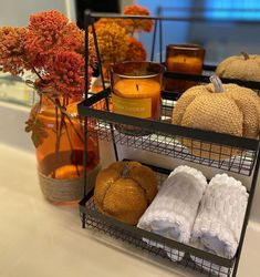 three tiered trays holding candles, towels and pumpkins on a counter top