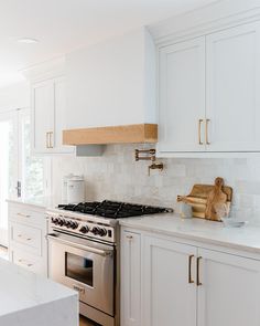 a kitchen with white cabinets and stainless steel stove top oven, wooden cutting board on the counter