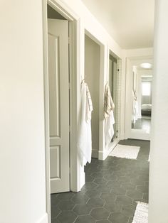 a bathroom with white towels hanging on the wall and black tile flooring in front of it