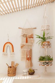 three macrame hangings with plants and potted plants on them in front of a white wall