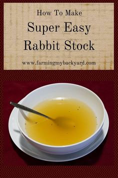 a white bowl filled with yellow liquid on top of a red table next to a spoon