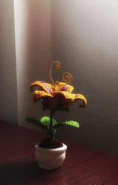 a crocheted flower in a pot on a table