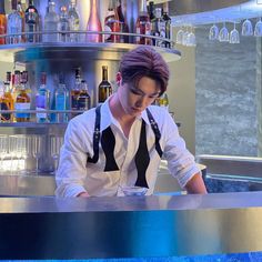 a man sitting at a bar with bottles behind him