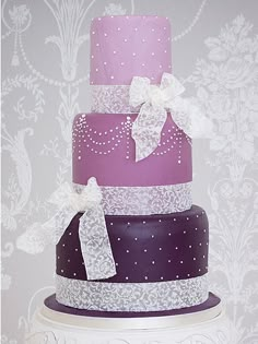 a three tiered cake with purple and white frosting