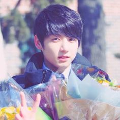 a young man is holding several bags and giving the peace sign