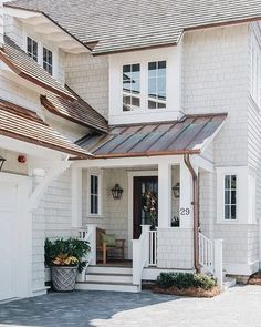 a large white house with two garages on the front and one story home in the back