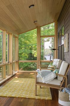 the sun shines through the large windows on this porch with a chair and rug