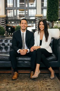 a man and woman sitting on a black couch