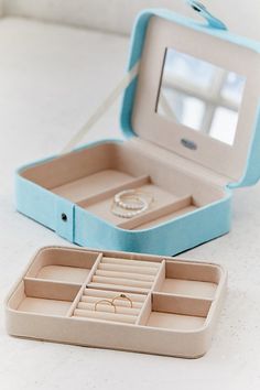 an open jewelry box sitting on top of a table next to a watch and ring box