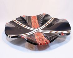 a black and orange plate with designs on it's sides sitting on a white surface