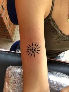 a woman's arm with a tattoo on it that has an image of the sun