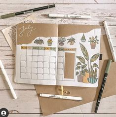 an open planner book sitting on top of a wooden table next to markers and pens