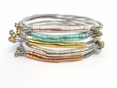 This music inspired bangle bracelet is custom made with recycled guitar strings in your size and favorite color! These are truly unique pieces of handmade jewelry that make the perfect gift for music lovers, guitar players, musicians, concertgoers and the rockstars in your life! ⚡ D E T A I L S ⚡ ✦ Guitar string bracelet wrapped in wire - choose your favorite color from 13 options! ✦ Size: Made-to-order in sizes XS-XXL. (This is a bangle bracelet and slides over the hand. Please measure the widest part of your hand around the knuckles.) XS - 7" S - 7.5" M - 7.75" L - 8 XL - 8.25" XXL - 8.75" ✦ Guitar string is flexible, but does not stretch or adjust in size. If it's not a good fit, no worries! You can exchange it for a different size within 14 days. ✦ Free Shipping: Your order ships fast Music Festival Jewelry, Guitar Bracelet, Guitar String Jewelry, Guitar String Bracelet, Guitar Pics, Guitar Players, Music Jewelry, Festival Jewelry, Eco Friendly Jewelry