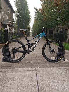 a blue and black mountain bike parked on the sidewalk