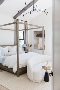 a white bed sitting in a bedroom on top of a carpeted floor next to a window