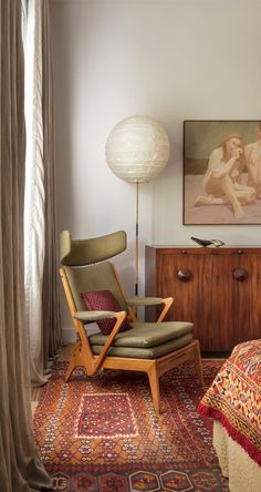 a bedroom with a chair, rug and painting on the wall