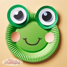 a green paper plate with googly eyes and a frog's face on it