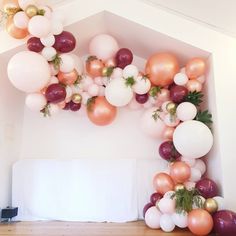 balloons and greenery are hanging from the ceiling in this party - themed room, complete with an arch