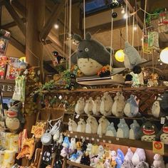 many stuffed animals and toys are on display in a store with lights hanging from the ceiling