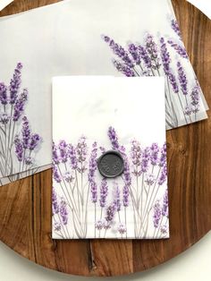 three napkins with purple flowers on them sitting on a wooden plate next to a wax stamp