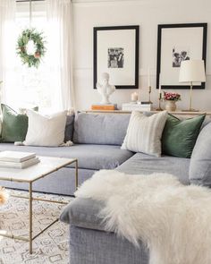 a living room filled with furniture and christmas wreath on the window sill in front of two windows