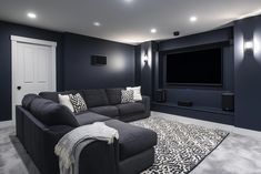 a living room with a gray couch and white rug in front of a flat screen tv