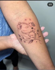 a woman's arm with a tattoo on it that has a bear and flowers