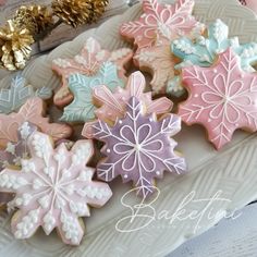 several decorated cookies are on a plate with gold and pink decorations in the shape of snowflakes