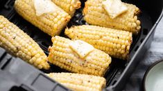 grilled corn on the cob with butter and seasoning in a black container