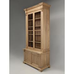 a tall wooden bookcase sitting on top of a white floor next to a gray wall