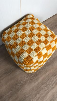 an orange and white blanket sitting on top of a floor next to a wooden floor