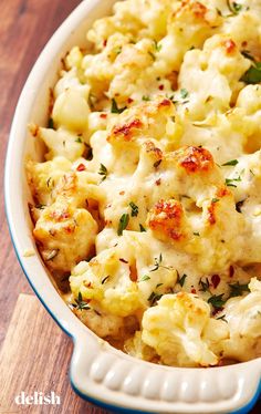 a casserole dish filled with macaroni and cheese, garnished with fresh herbs