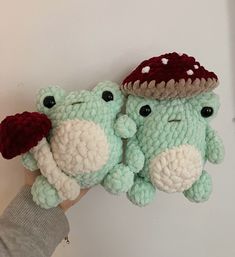 two crocheted stuffed animals with hats on their heads, one is green and the other is red