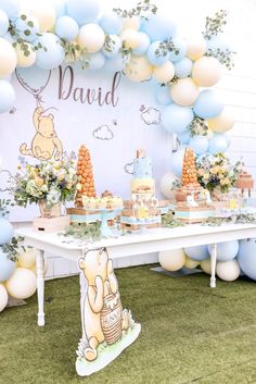 a winnie the pooh birthday party with balloons and desserts